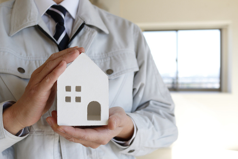 白い家の模型を持つ男性